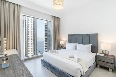 a bedroom with a large bed and large windows at Spacious 2 Bedroom on High Floor in Creek Horizon - Allsopp&Allsopp in Dubai