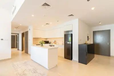 a kitchen with white cabinets and a black refrigerator at Spacious 2 Bedroom on High Floor in Creek Horizon - Allsopp&Allsopp in Dubai