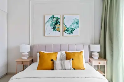 a bedroom with a bed with three paintings on the wall at Silkhaus furnished 1BDR in Downtown new tower in Dubai
