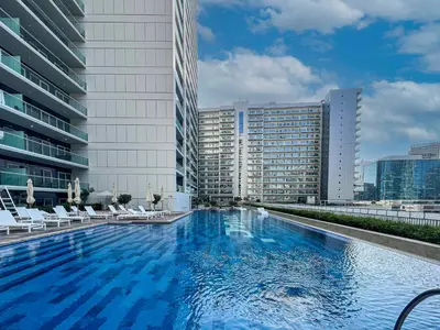 a large swimming pool with chairs and a building at AXINITE - Brand New! Warm Cozy 1 Bed HIGH FLOOR Downtown Dubai CANAL VIEW in Dubai