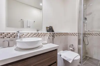 a white bathroom with a sink and a shower at Reva Residences - One Bedroom Apartment by the S Holiday Homes in Dubai
