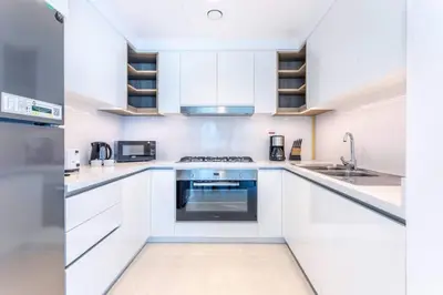 a white kitchen with white cabinets and appliances at 3BR facing Dubai Mall 5 min walk to Burj Khalifa in Dubai