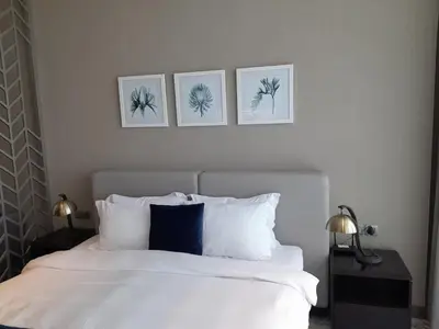 a bedroom with a white bed with three pictures on the wall at Canal View, Luxurious Studio In Downtown Dubai in Dubai