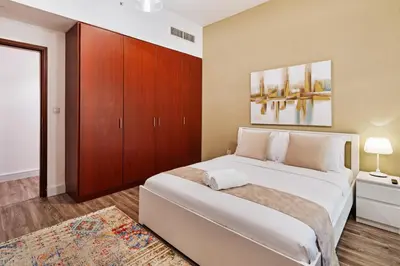 a bedroom with a large white bed and wooden cabinets at La Buena Vida Holiday Homes - Deluxe, very spacious 5 Bedroom plus maidroom in Best location of JBR, Near to Beach, Marina and Tram station in Dubai