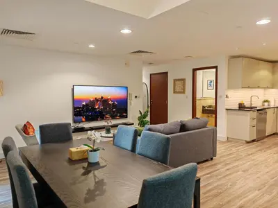 a living room with a table and a tv on the wall at La Buena Vida Holiday Homes - Deluxe, very spacious 5 Bedroom plus maidroom in Best location of JBR, Near to Beach, Marina and Tram station in Dubai