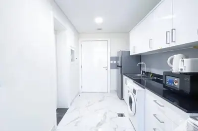 a kitchen with white cabinets and a black appliances at Cozy Spacious Studio With Balcony Dubai in Dubai