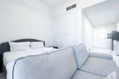 a white bedroom with a bed and a couch at Cozy Spacious Studio With Balcony Dubai in Dubai