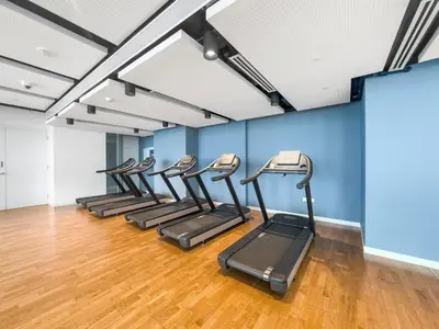 a row of treadmills in a gym with blue walls at New 2 bedroom in Bluewaters with Direct Sea View in Dubai