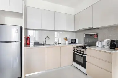 a kitchen with white cabinets and a stainless steel appliances at Silkhaus in Burj Royale, stunning 1BR in Downtown premium tower in Dubai