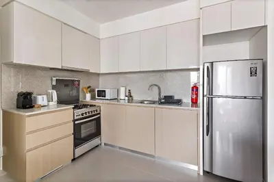 a kitchen with white cabinets and a stainless steel refrigerator at Silkhaus sophisticated 1BDR in Downtown premium tower in Dubai