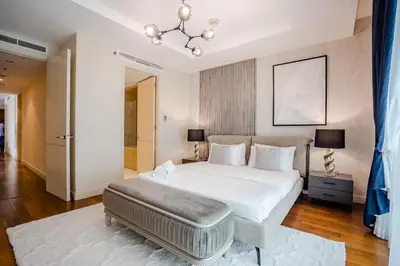 a bedroom with a large white bed and a chandelier at Nasma Luxury Stays - Limestone House in Dubai