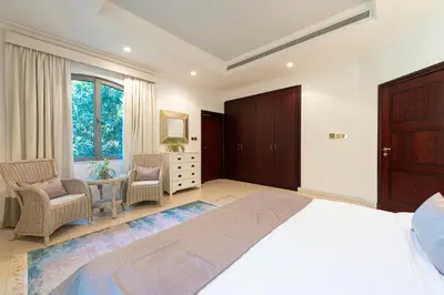 a bedroom with a large bed and a desk and chairs at Palm Jumeirah Beachfront private pool villa 5 BR & 1 maids room with access to beach in Dubai