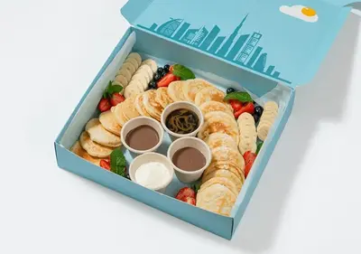 a blue lunch box filled with pastries and fruit at Cosmos Living Dubai Arch Tower Pool, Gym & Balcony in Dubai