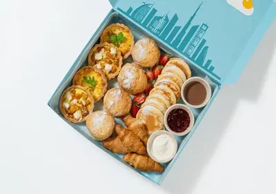 a lunch box filled with pastries and other foods at Cosmos Living Dubai Arch Tower Pool, Gym & Balcony in Dubai
