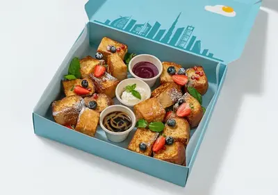 a box filled with pastries with fruit and dipping sauces at Cosmos Living Dubai Arch Tower Pool, Gym & Balcony in Dubai