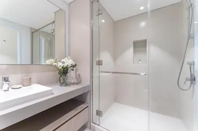 a white bathroom with a sink and a shower at Vogue Creek Harbour The Grand Waterfront Living close to Downtown, Burj Khalifa and Dubai Mall, Two Bedroom Apartment with Balcony, Canal and Vibrant Community View, Access to all Amenities in Dubai