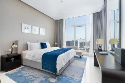 a bedroom with a bed and a desk and a large window at Gala Guests - Maison Prive Canal View Collection in Dubai
