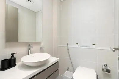 a white bathroom with a sink and a toilet at Gala Guests - Maison Prive Canal View Collection in Dubai