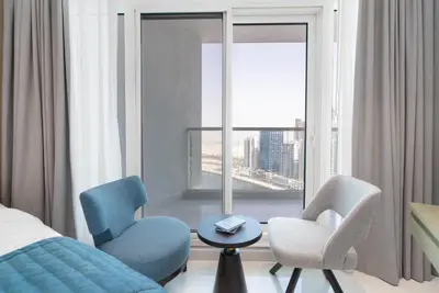 a bedroom with a bed and two chairs and a window at Gala Guests - Maison Prive Canal View Collection in Dubai