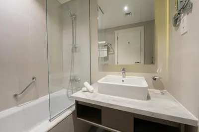 a white bathroom with a sink and a shower at ALiving Stylish Studio with Partial Burj & Canal Views- Prive , Business bay 713 in Dubai