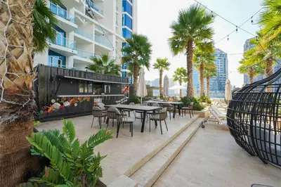 an outdoor patio with tables and chairs and palm trees at ALiving Stylish Studio with Partial Burj & Canal Views- Prive , Business bay 713 in Dubai