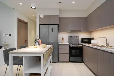 a kitchen with brown cabinets and a white counter top at Maison Privee - Luxury 2Bedroom with Burj Khalifa & Fountain Views in Dubai