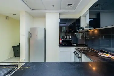 a kitchen with black and white cabinets and a refrigerator at Marco Polo - Enjoy comfort and class near Burj Khalifa in Dubai