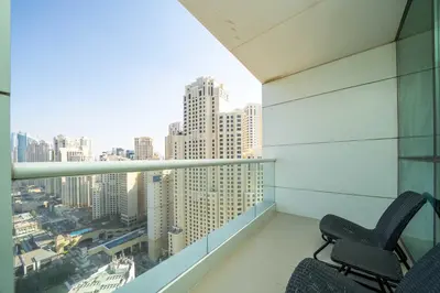 a chair on a balcony with a view of a city at Beachfront 1 Bed with Full JBR View in Dubai