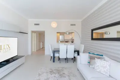 a white living room with a white couch and a table at Beachfront 1 Bed with Full JBR View in Dubai