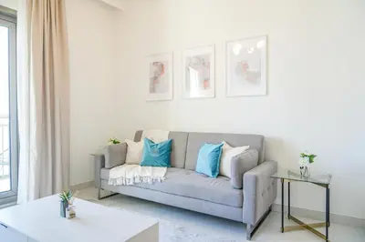 a living room with a gray couch with blue pillows at Elegant Apartment With Balcony Amidst Vibrant Area in Dubai