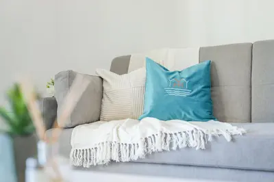 a gray couch with a blue pillow on it at Elegant Apartment With Balcony Amidst Vibrant Area in Dubai