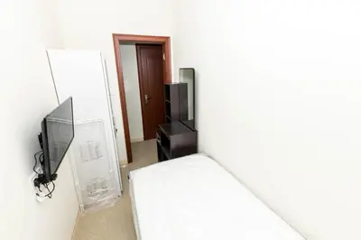 a white room with a bed and a television at Roomy Dubai Hostel Small Rooms and Partitions at Marina in Dubai
