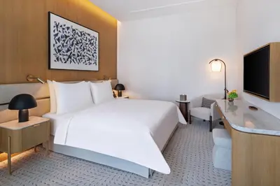 a hotel room with a large white bed and a desk at Vida Creek Beach Hotel in Dubai