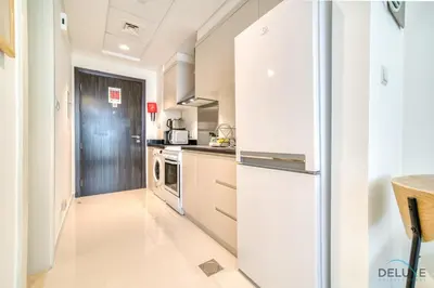 a kitchen with white appliances and a refrigerator at Opulent Studio at Carson C DAMAC Hills Dubailand by Deluxe Holiday Homes in Dubai