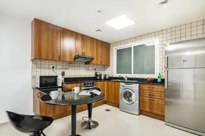 a kitchen with a table and a stainless steel refrigerator at The Smart Concierge - Princess tower in Dubai
