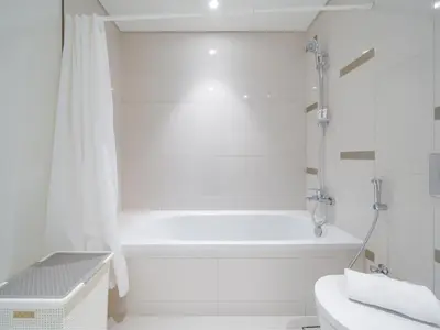 a white bathroom with a tub and a toilet at Exceptional 2BR-Private Beach Access-Palm Jumeirah in Dubai