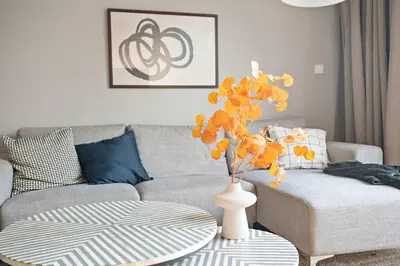a living room with a couch and a vase with yellow flowers at Silkhaus new 1BDR in Executive Residence 2 in Dubai