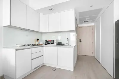 a white kitchen with white cabinets and a stove at Silkhaus new studio in JVC with queen Bed in Dubai