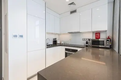 a kitchen with white cabinets and a microwave at Fully Furnished I Lagoons View I District One in Dubai