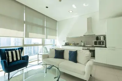 a living room with a couch and a glass table at Nasma Luxury Stays - White Haven Studio With Charming Cityscape Views in Dubai