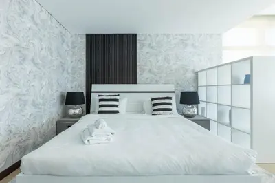 a bedroom with a white bed with two lamps at Nasma Luxury Stays - White Haven Studio With Charming Cityscape Views in Dubai