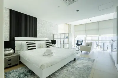 a white bedroom with a large bed and a dining room at Nasma Luxury Stays - White Haven Studio With Charming Cityscape Views in Dubai