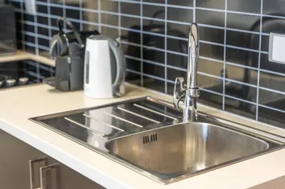 a stainless steel sink in a kitchen with blue tiles at Hidden Gem 1 Bedroom apt in Dubai Sport City in Dubai