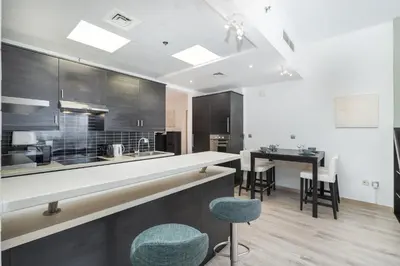 a kitchen with a counter and chairs and a table at Hidden Gem 1 Bedroom apt in Dubai Sport City in Dubai