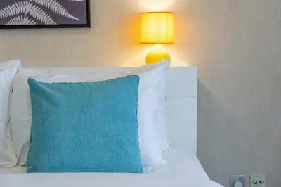 a bed with a blue pillow and a lamp on it at Hidden Gem 1 Bedroom apt in Dubai Sport City in Dubai