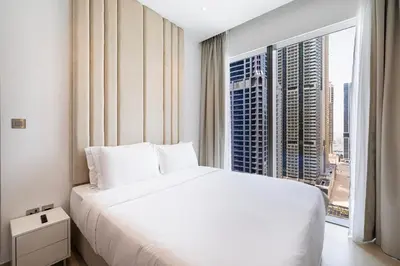 a bedroom with a white bed and a large window at Marina Gate One Bedroom Apartment in Dubai