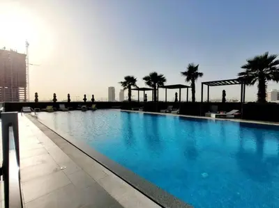 a swimming pool on top of a building with palm trees at Studio in JVC - Heart of Dubaï - Bloom Height in Dubai