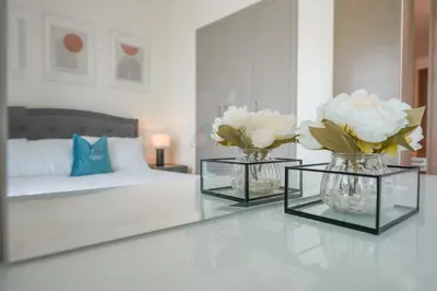a living room with two vases with flowers on a table at Bright Apartment With Panoramic CityScape Views in Dubai