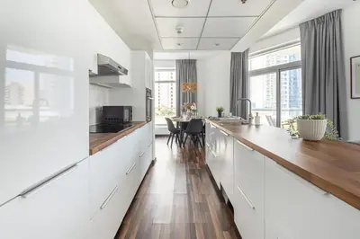 a kitchen with white cabinets and a wooden counter top at Frank Porter - Bonaire Tower in Dubai