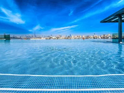 a swimming pool with a city skyline in the background at Fantastic 2BD apartment in Dubai Creek Harbour in Dubai